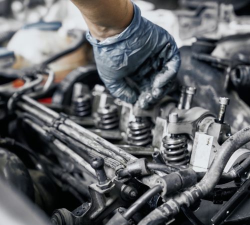Technician's gloved hand inspecting valve springs and injectors on a diesel engine during a diagnostic at Sur-Flow Hydraulics & Equipment Repair
